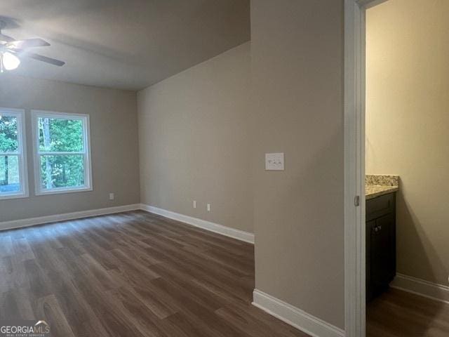 interior space with dark wood-type flooring, a ceiling fan, and baseboards