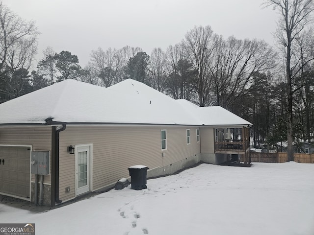 snow covered back of property featuring a garage and crawl space