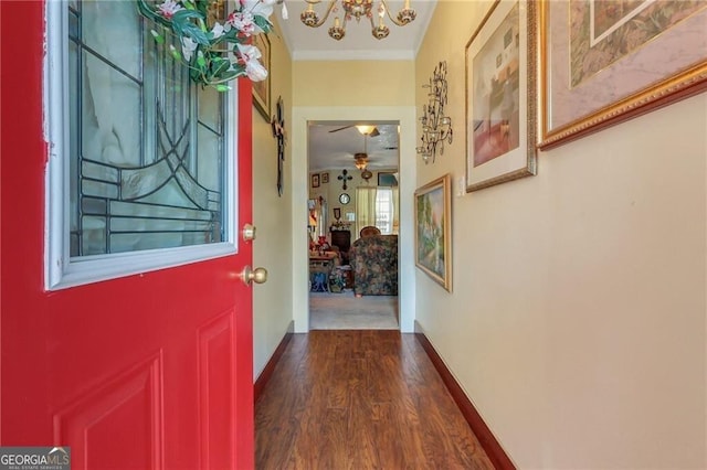 entryway featuring ornamental molding, dark wood-style flooring, baseboards, and an inviting chandelier