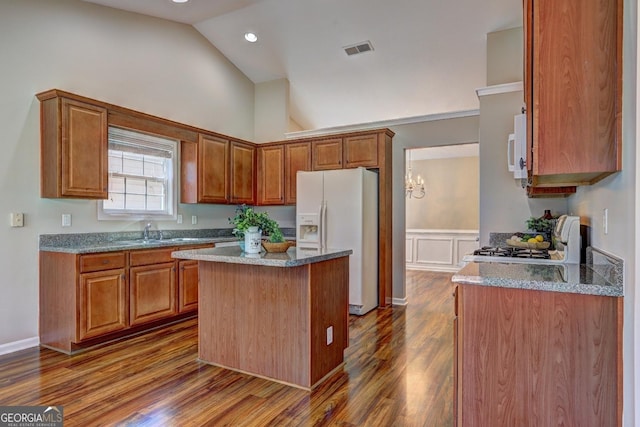 kitchen with stone countertops, white appliances, a kitchen island, visible vents, and brown cabinetry