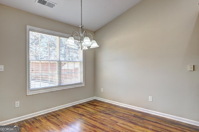 spare room with an inviting chandelier, baseboards, visible vents, and dark wood-type flooring