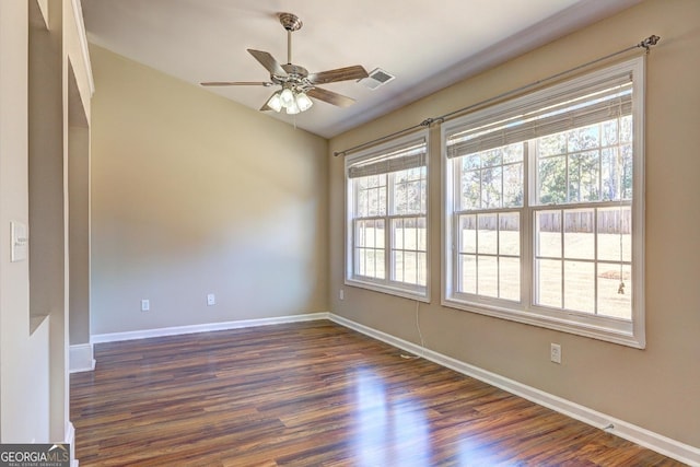 spare room with a ceiling fan, dark wood finished floors, visible vents, and baseboards