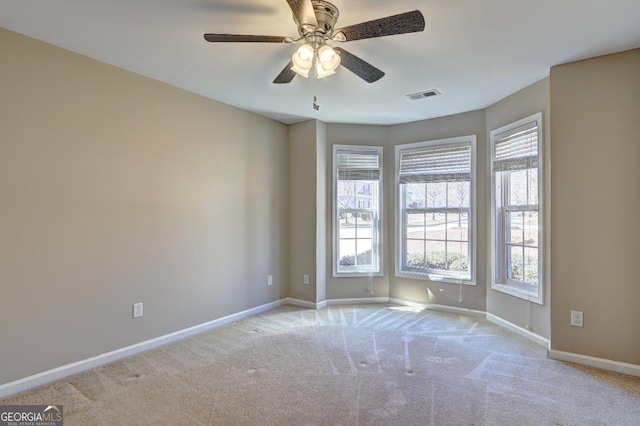 empty room featuring baseboards, a ceiling fan, visible vents, and light colored carpet