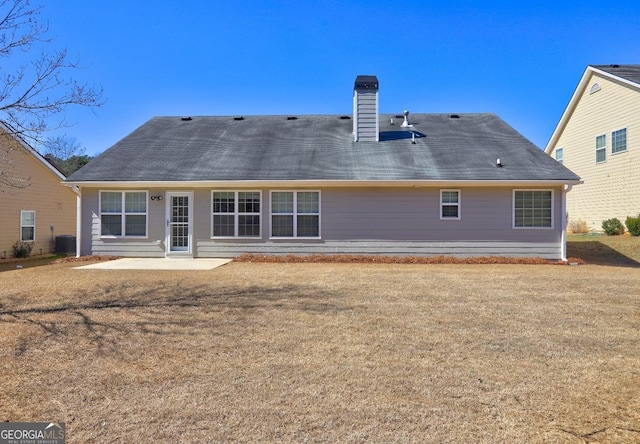 back of house with a patio, a yard, a chimney, and central air condition unit