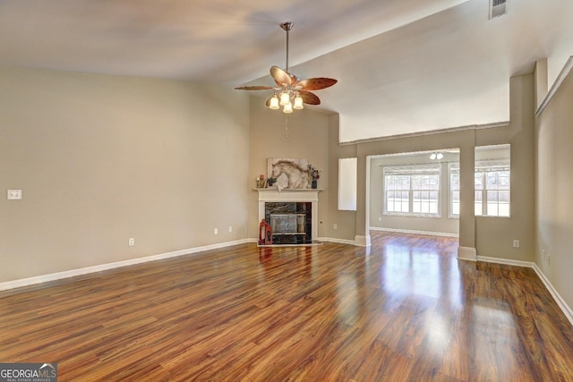 unfurnished living room featuring baseboards, dark wood finished floors, ceiling fan, a fireplace, and high vaulted ceiling