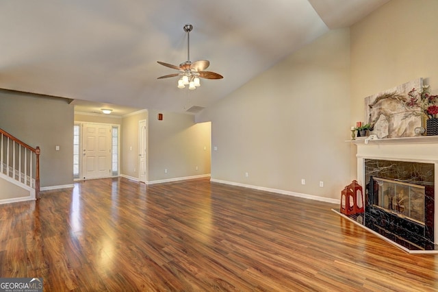 unfurnished living room featuring stairs, a premium fireplace, baseboards, and wood finished floors