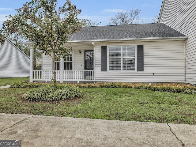 view of front of property with covered porch, a shingled roof, and a front yard