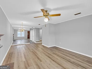 unfurnished living room with ceiling fan with notable chandelier, visible vents, light wood-style flooring, and baseboards