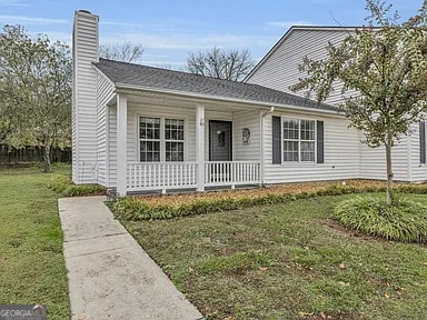 view of front of home featuring a porch, a front yard, and a chimney