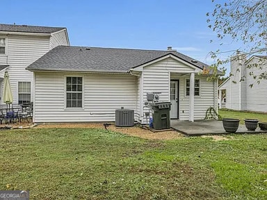 rear view of house featuring a yard, central AC, and a patio area