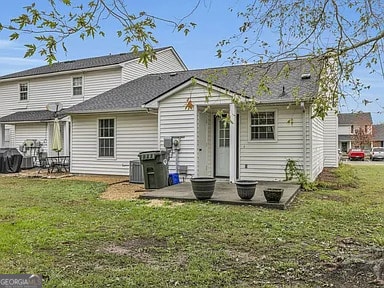 back of property featuring a patio area, cooling unit, and a lawn