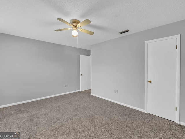 carpeted empty room with ceiling fan, a textured ceiling, visible vents, and baseboards