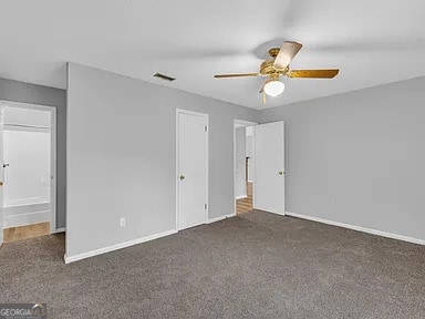 unfurnished bedroom with ceiling fan, baseboards, visible vents, and dark colored carpet