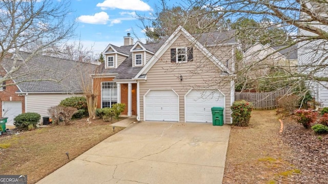 view of front of house featuring driveway, a garage, a chimney, and fence