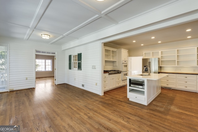 kitchen with a kitchen island with sink, stainless steel appliances, light countertops, dark wood-style floors, and open shelves