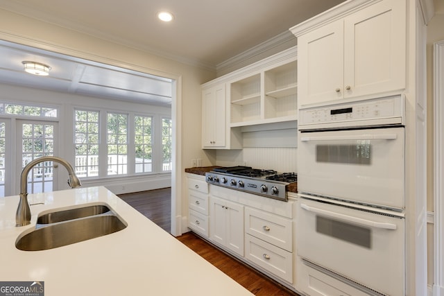 kitchen with white cabinets, stainless steel gas cooktop, white double oven, and a sink