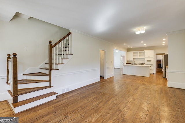 unfurnished living room featuring visible vents, stairs, crown molding, light wood-style floors, and recessed lighting