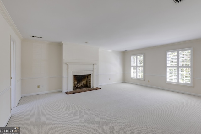 unfurnished living room featuring a fireplace with raised hearth, ornamental molding, visible vents, and light colored carpet