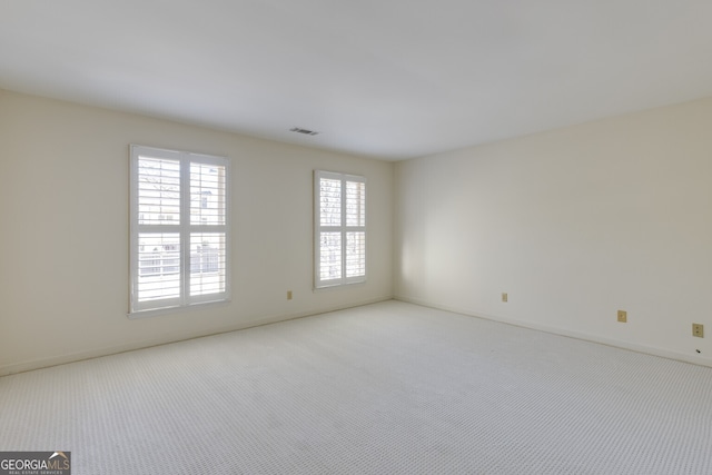 spare room featuring visible vents and light colored carpet