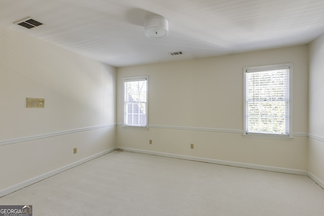 spare room with light carpet, visible vents, and baseboards