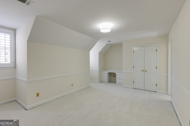 bonus room featuring lofted ceiling, light colored carpet, visible vents, and baseboards