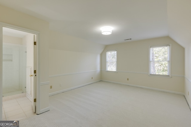 bonus room featuring light colored carpet, vaulted ceiling, visible vents, and light tile patterned floors