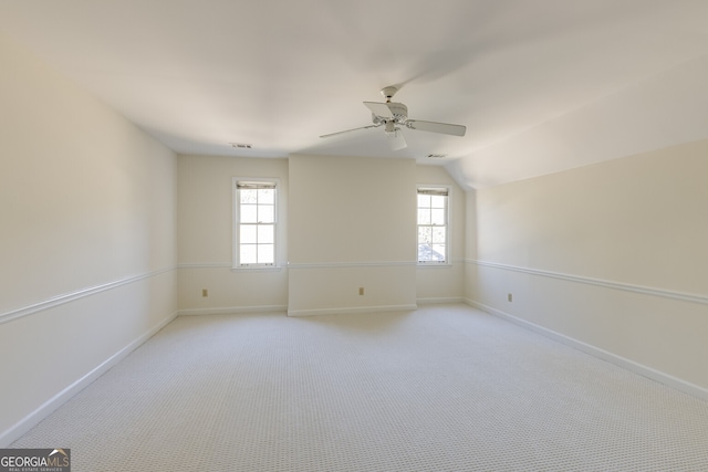 unfurnished room with visible vents, baseboards, a ceiling fan, light colored carpet, and lofted ceiling