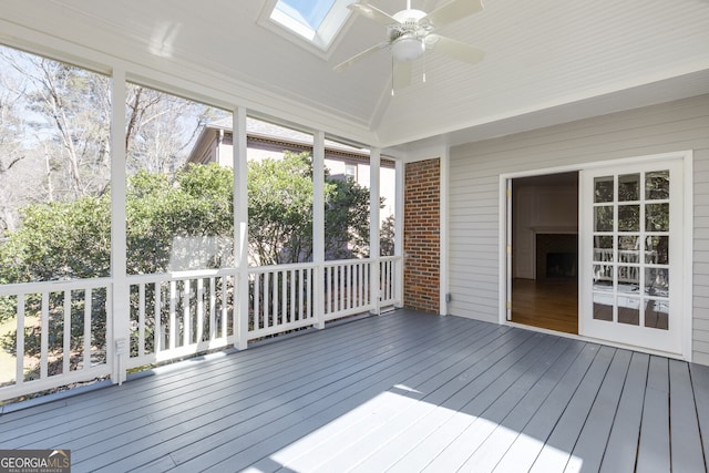 unfurnished sunroom featuring vaulted ceiling with skylight and a ceiling fan