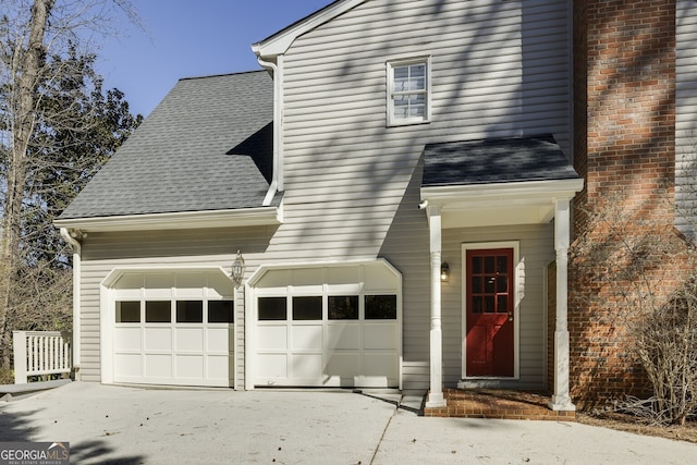 view of front of house with a shingled roof, driveway, and a garage