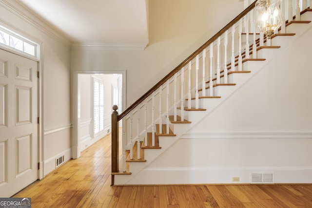 entrance foyer featuring crown molding, visible vents, and wood finished floors