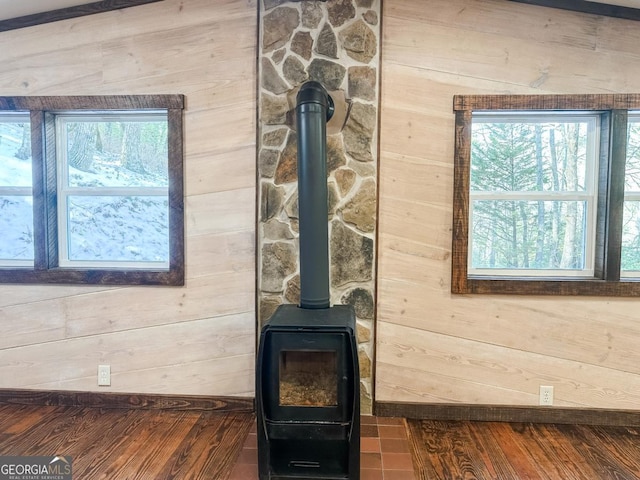 details featuring a wood stove, wooden walls, baseboards, and wood finished floors