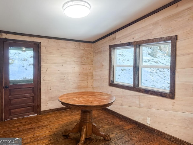 interior space with wood walls, baseboards, ornamental molding, and wood finished floors