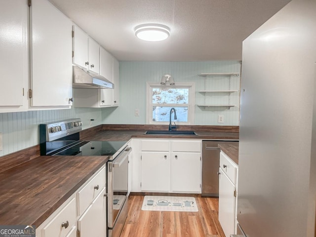 kitchen featuring appliances with stainless steel finishes, white cabinetry, a sink, and under cabinet range hood