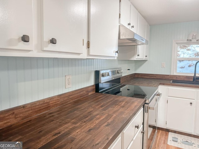 kitchen with electric stove, white cabinetry, a sink, wood counters, and under cabinet range hood