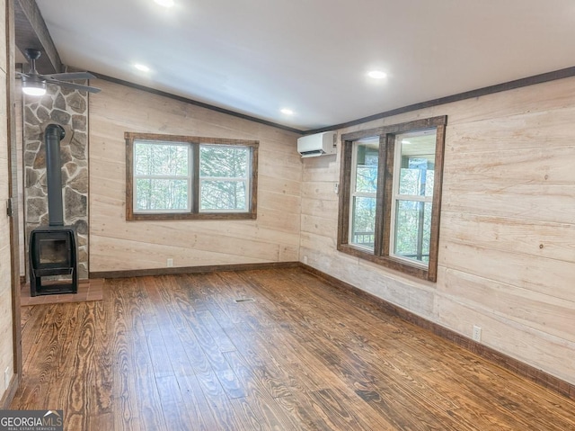 unfurnished living room with lofted ceiling, wood finished floors, a wood stove, an AC wall unit, and wood walls