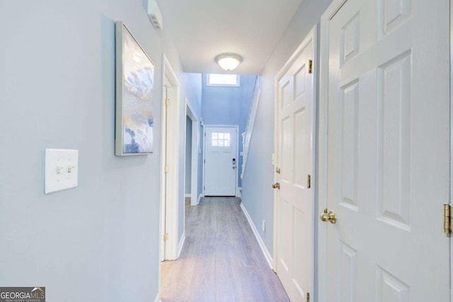 corridor with baseboards and wood finished floors