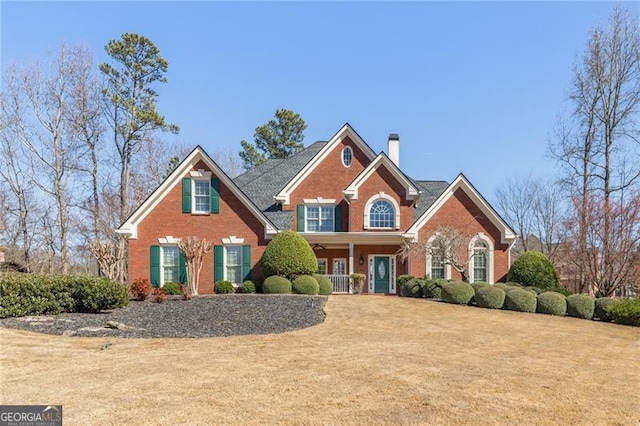 view of front facade with a chimney, a front lawn, and brick siding