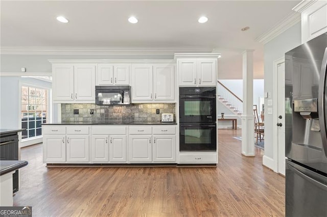 kitchen with black appliances, dark countertops, white cabinetry, and crown molding