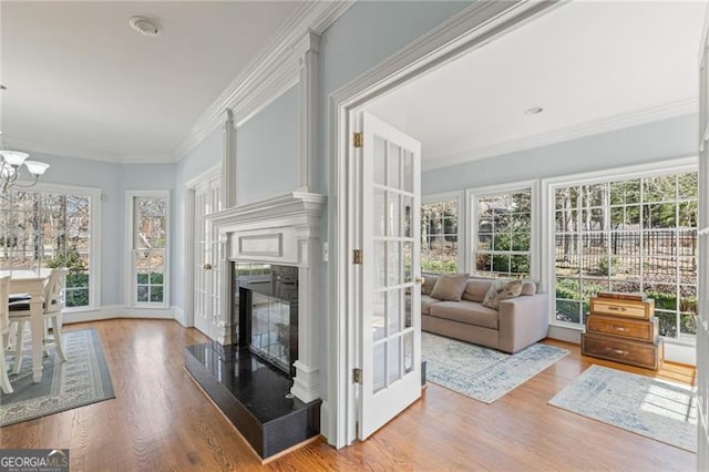 sunroom featuring a chandelier and a fireplace with raised hearth