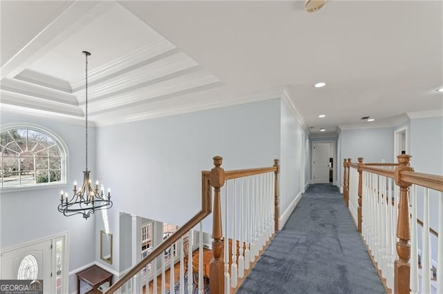 corridor featuring a notable chandelier, carpet floors, an upstairs landing, baseboards, and crown molding