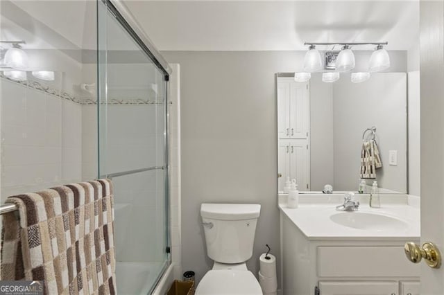 bathroom with toilet, combined bath / shower with glass door, and vanity