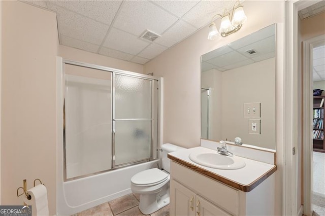 bathroom with a drop ceiling, toilet, vanity, visible vents, and tile patterned floors