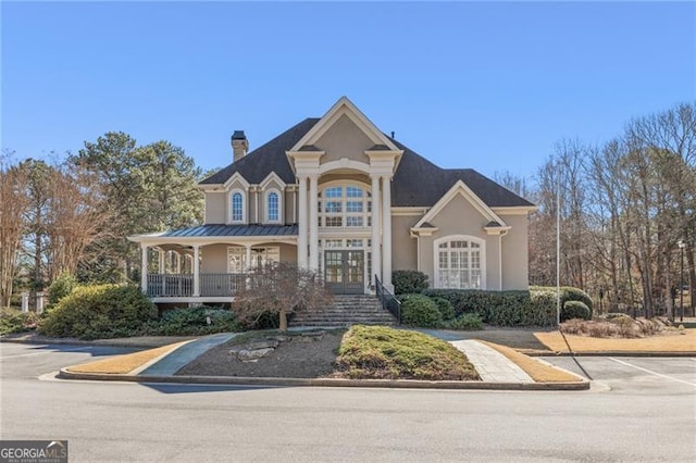 view of front facade featuring uncovered parking, french doors, a chimney, and stucco siding