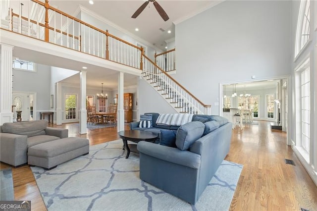 living room featuring light wood-style floors, a high ceiling, stairway, and crown molding