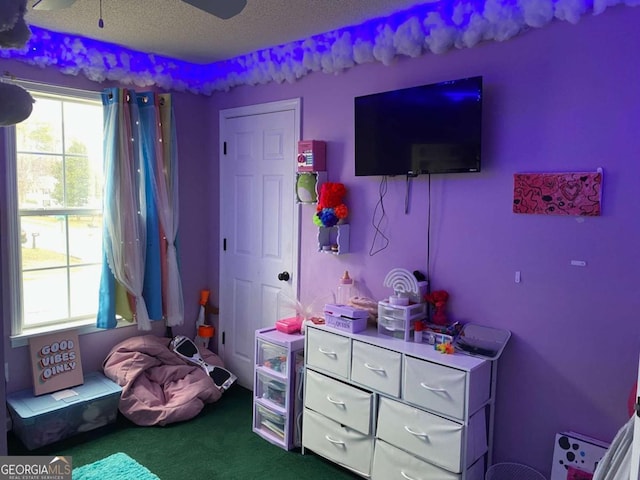 recreation room with dark colored carpet, ceiling fan, and a textured ceiling