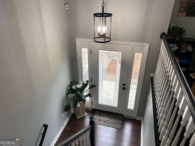 entryway with stairs, dark wood finished floors, a towering ceiling, and baseboards