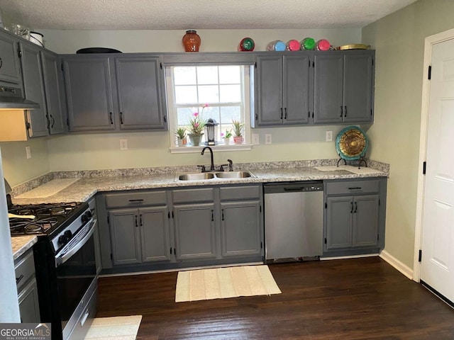 kitchen with stainless steel appliances, a sink, ventilation hood, gray cabinets, and dark wood-style floors