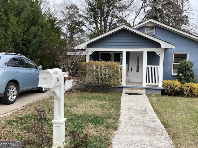 bungalow-style house with covered porch, brick siding, and a front lawn