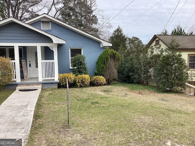 exterior space featuring a porch, a front yard, and brick siding