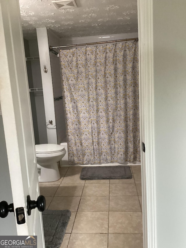 1141 N Clark St, Milledgeville, GA 31061 - bathroom with visible vents, toilet, tile patterned flooring, shower / bathtub combination with curtain, and a textured ceiling
